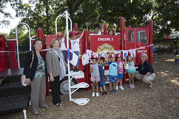 The newest addition to the Child Care Center is a beautiful fire truck-themed playground. From left: Roseann Bucciarelli, dean of Continuing Education; MCC President Joann La Perla-Morales; with (top row) Alana and Athena Asimakis, Nadia Kaminsky, Aidan Magner. Bottom row: Jayahni Alvarez, Thiago Juarez, Raymond Vetter, Mia Izurieta, Aubrey Gomez, and Mary Jo Tivenan-Mackintosh, Child Care director.