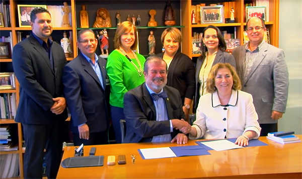 Jorge Ivan Vélez Arocho, president of PUCPR, with Joann La Perla-Morales, president of MCC, surrounded by officials from PUCPR.